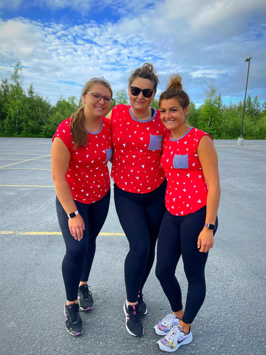 Three women standing side by side smiling.