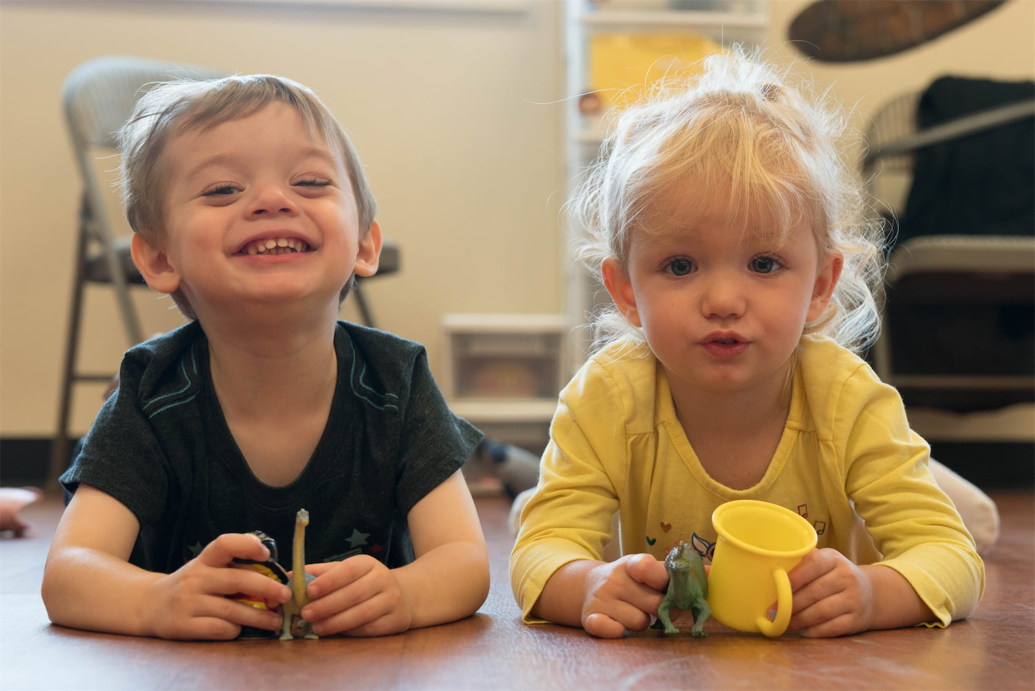 Two children making playful faces while lying on their stomachs