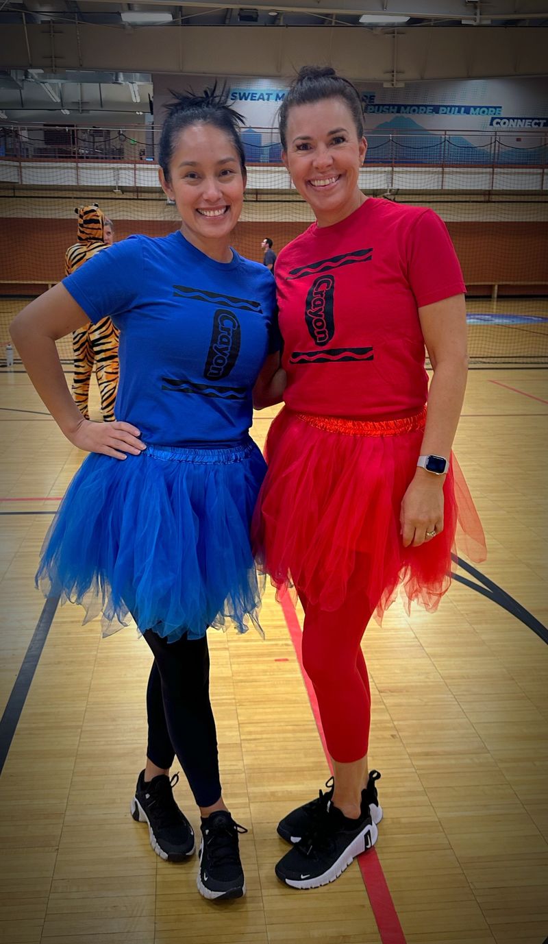 Two members smiling in colorful costumes at Grizzly Family Fitness.